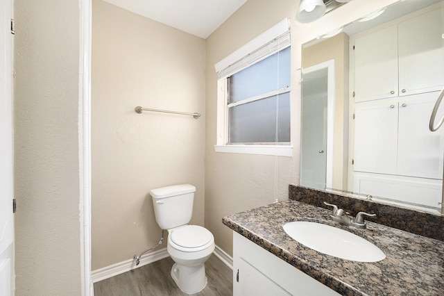 bathroom featuring vanity, toilet, wood finished floors, and baseboards