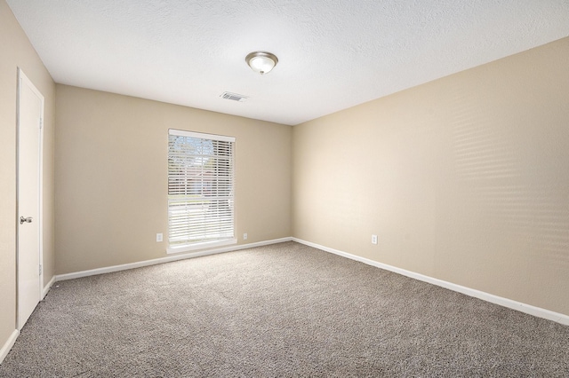 spare room featuring visible vents, carpet flooring, a textured ceiling, and baseboards