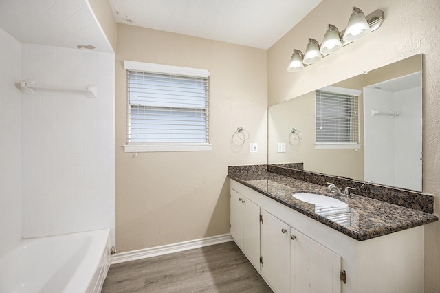 full bathroom featuring baseboards, shower / washtub combination, wood finished floors, and vanity