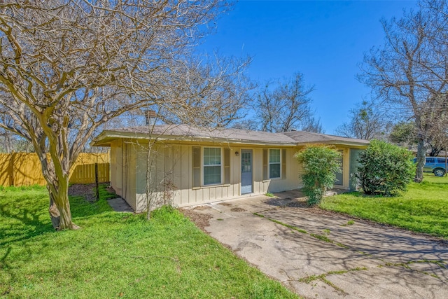 ranch-style house featuring board and batten siding, driveway, a front lawn, and fence