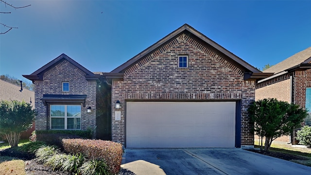 view of front of home featuring brick siding, an attached garage, and driveway