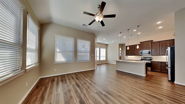 kitchen featuring visible vents, dark brown cabinets, open floor plan, light countertops, and appliances with stainless steel finishes