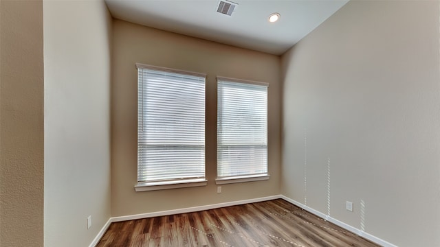 empty room featuring wood finished floors, visible vents, and baseboards