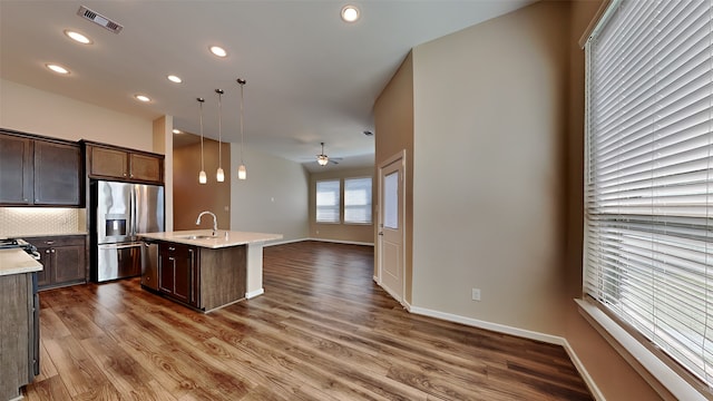 kitchen featuring wood finished floors, visible vents, a sink, dark brown cabinetry, and stainless steel refrigerator with ice dispenser