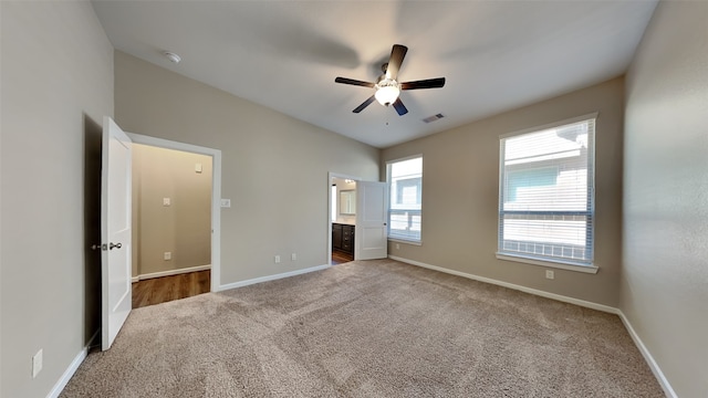 unfurnished bedroom featuring a ceiling fan, carpet, visible vents, baseboards, and connected bathroom