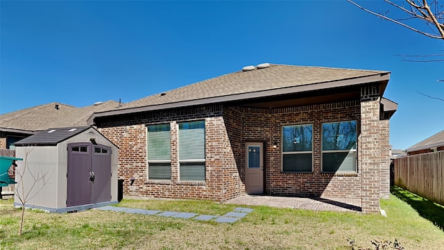 back of property featuring brick siding, fence, a yard, an outbuilding, and a storage unit