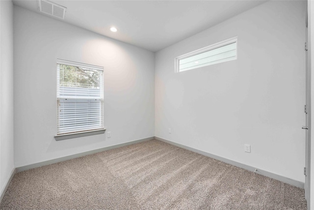 carpeted spare room with baseboards, visible vents, and a wealth of natural light