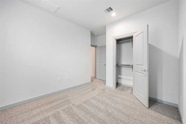 unfurnished bedroom with baseboards, visible vents, a closet, and light carpet