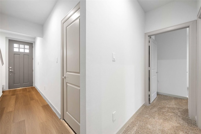 hallway featuring light wood-style flooring and baseboards