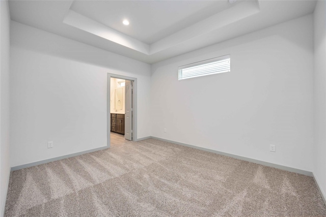 spare room with a raised ceiling, recessed lighting, baseboards, and light carpet