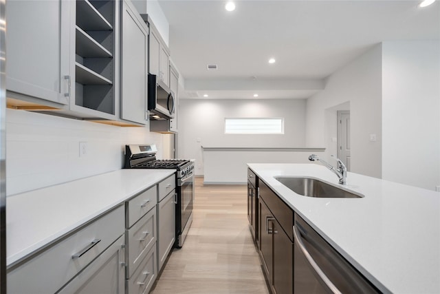 kitchen with light wood-type flooring, light countertops, recessed lighting, stainless steel appliances, and a sink