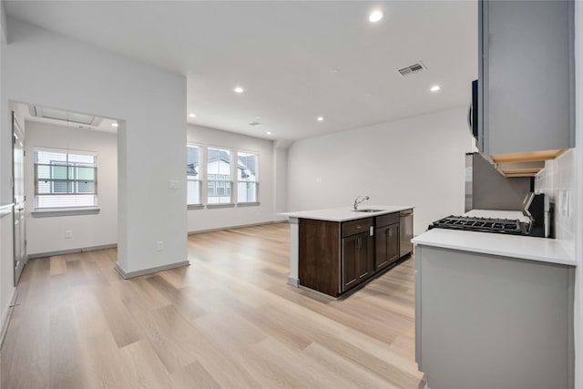 kitchen with visible vents, light wood finished floors, stainless steel appliances, light countertops, and dark brown cabinets