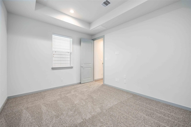 carpeted empty room featuring a tray ceiling, recessed lighting, baseboards, and visible vents