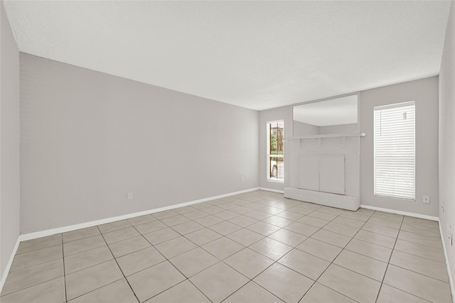 spare room featuring light tile patterned flooring and baseboards