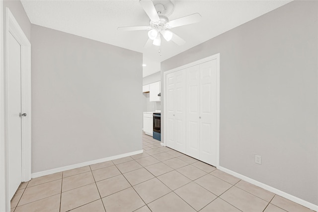 empty room with baseboards, ceiling fan, and light tile patterned flooring