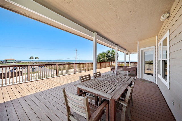 deck with outdoor dining area and a water view