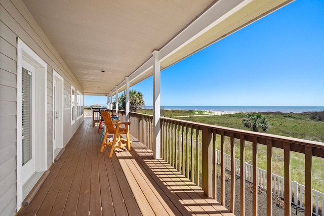 wooden terrace featuring a beach view and a water view