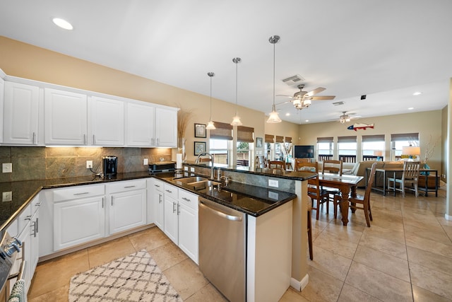 kitchen featuring backsplash, open floor plan, a peninsula, stainless steel dishwasher, and a sink