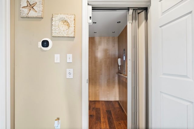 hallway featuring elevator and dark wood-style flooring