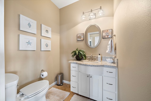 half bathroom featuring toilet, vanity, and baseboards