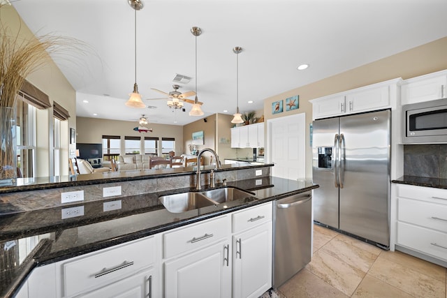 kitchen featuring a sink, stainless steel appliances, decorative light fixtures, and white cabinetry