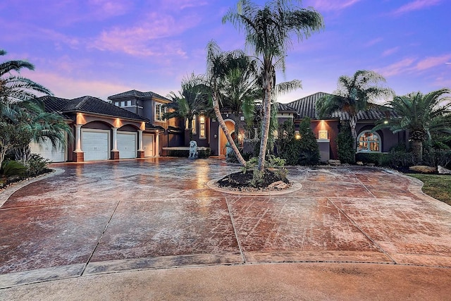 view of front of home featuring stucco siding, an attached garage, driveway, and a tiled roof