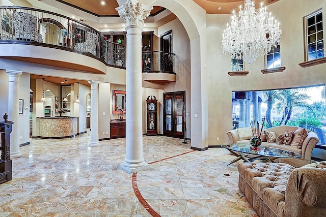 living area featuring an inviting chandelier, a high ceiling, baseboards, and ornate columns