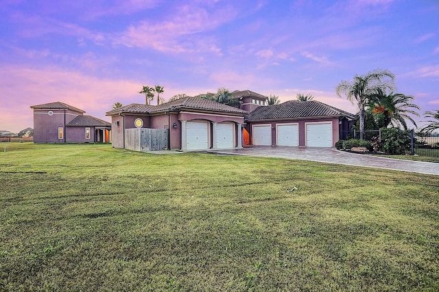 mediterranean / spanish home featuring fence, driveway, stucco siding, a tiled roof, and a lawn