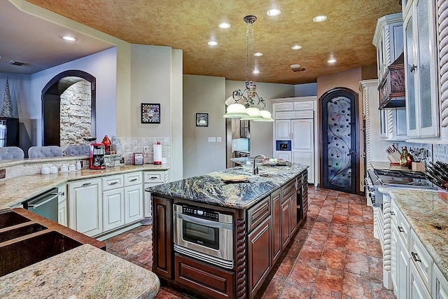 kitchen with high end range, white cabinets, a sink, and decorative backsplash