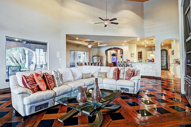 living room featuring arched walkways, a high ceiling, and ceiling fan