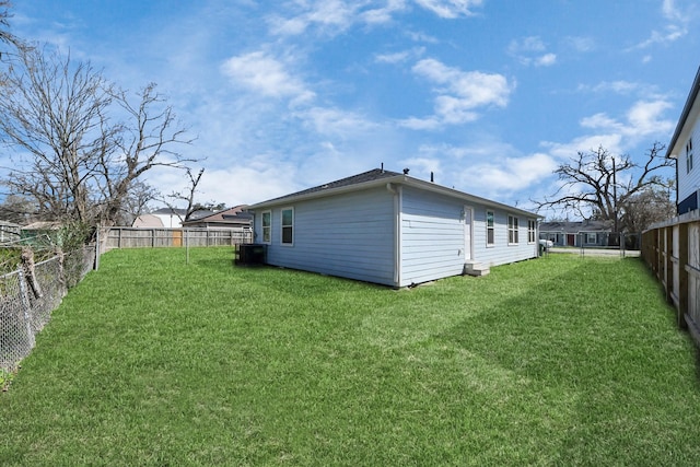 rear view of property featuring a yard, a fenced backyard, and central AC