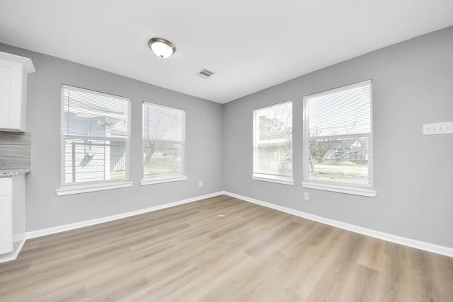 unfurnished room with visible vents, plenty of natural light, and baseboards