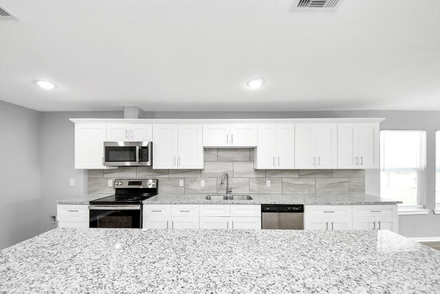 kitchen featuring a sink, stainless steel appliances, white cabinets, and decorative backsplash