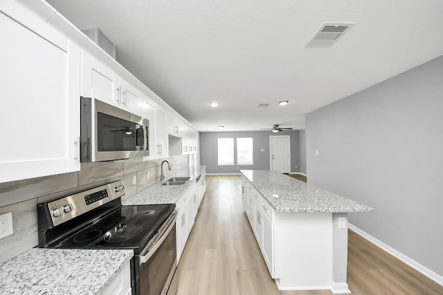 kitchen featuring visible vents, a center island, decorative backsplash, appliances with stainless steel finishes, and a sink