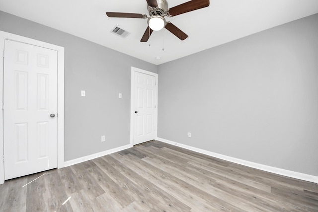 unfurnished bedroom with visible vents, ceiling fan, baseboards, and wood finished floors