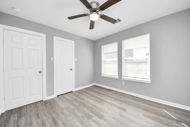 unfurnished bedroom featuring a ceiling fan, wood finished floors, visible vents, and baseboards