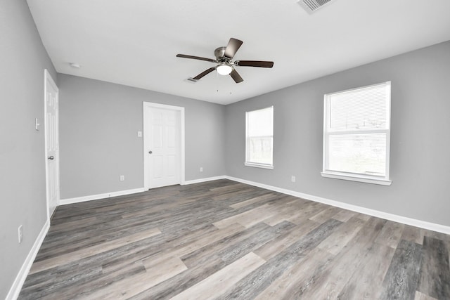 spare room featuring a ceiling fan, visible vents, wood finished floors, and baseboards