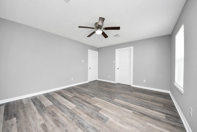 unfurnished room featuring visible vents, baseboards, wood finished floors, and a ceiling fan