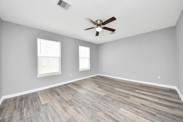 unfurnished room with ceiling fan, visible vents, baseboards, and wood finished floors