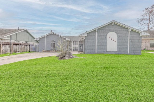 single story home featuring brick siding, concrete driveway, fence, and a front yard