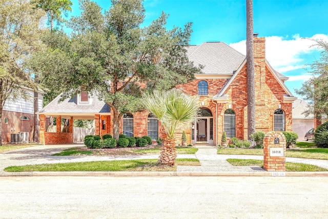 view of front of property featuring brick siding, a chimney, a shingled roof, and a carport