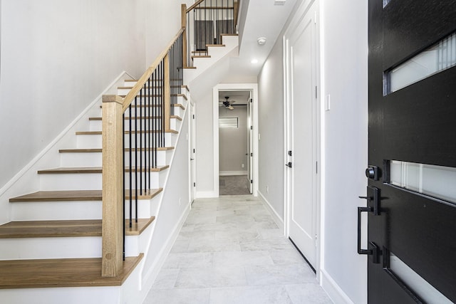 entrance foyer featuring ceiling fan, stairs, baseboards, and a towering ceiling