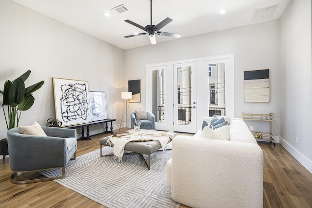 living area with visible vents, a ceiling fan, baseboards, and wood finished floors