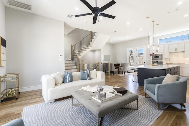 living area featuring visible vents, recessed lighting, stairs, and light wood-type flooring