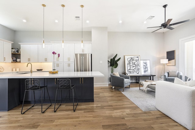 kitchen featuring high end fridge, a kitchen breakfast bar, open floor plan, white cabinetry, and light countertops