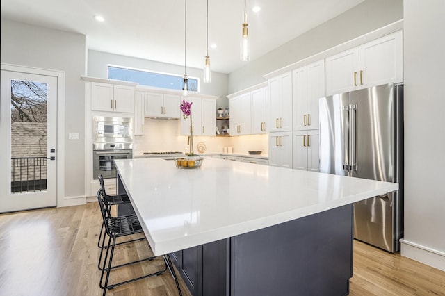 kitchen featuring white cabinetry, light wood-type flooring, backsplash, and stainless steel appliances