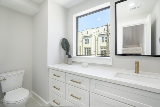 bathroom with visible vents, a healthy amount of sunlight, toilet, and vanity