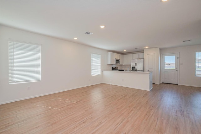 unfurnished living room featuring recessed lighting, baseboards, visible vents, and light wood-type flooring