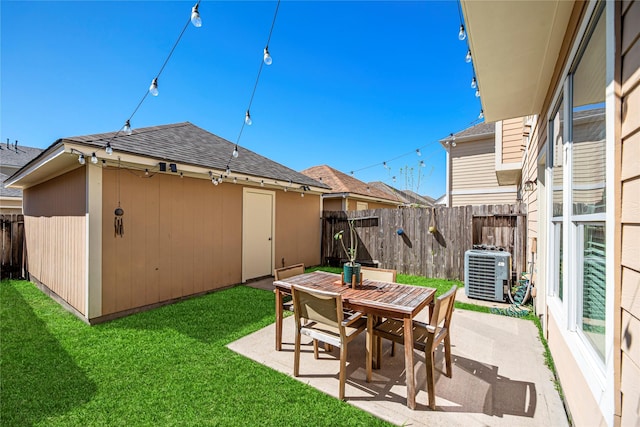 view of yard featuring a patio area, central AC unit, outdoor dining area, and a fenced backyard