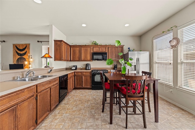 kitchen featuring brown cabinets, black appliances, light countertops, and a sink